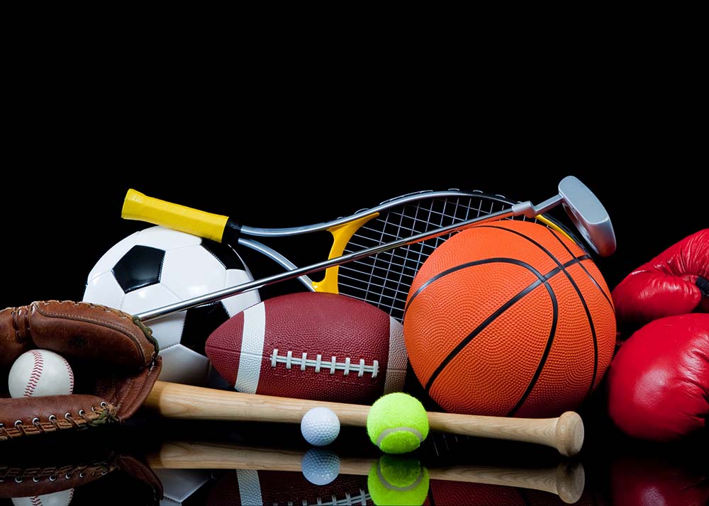 A group of sports equipment on black background including tennis, basketball, baseball, american fotball and soccer and boxing equipment on a black background with copy space